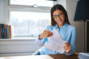 Woman smiling at her fake paystubs she received in the mail